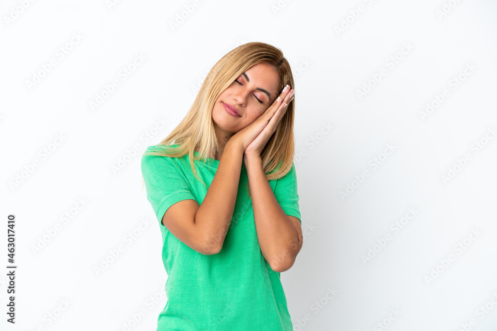 Blonde Uruguayan girl isolated on white background making sleep gesture in dorable expression Blonde Uruguayan girl isolated on white background making sleep gesture in dorable expression
