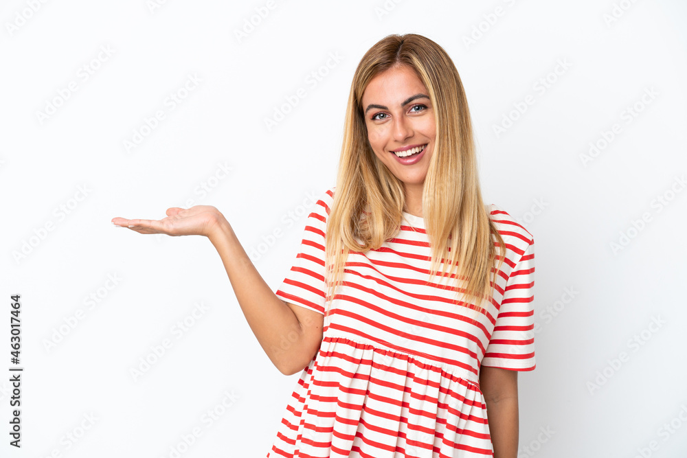 Blonde Uruguayan girl isolated on white background holding copyspace imaginary on the palm to insert an ad Blonde Uruguayan girl isolated on white background holding copyspace imaginary on the palm to insert an ad