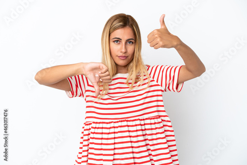 Blonde Uruguayan girl isolated on white background making good-bad sign. Undecided between yes or not © luismolinero