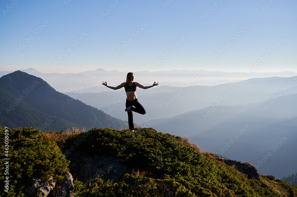 Front view of young attractive woman doing meditation on fresh air in the morning with beautiful landscape. Concept of meditation.