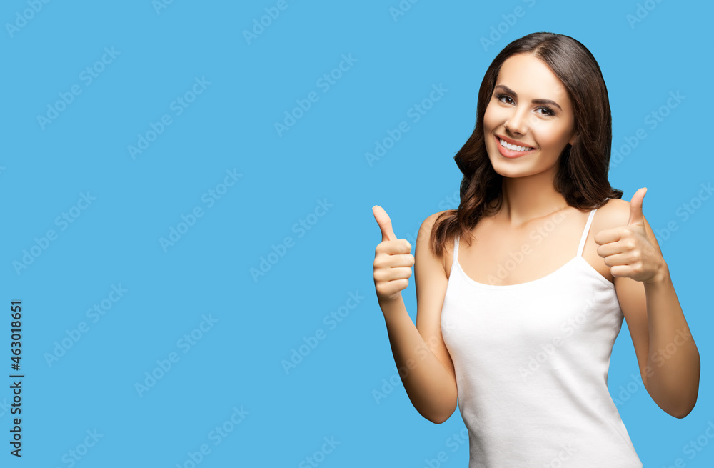 Photo of woman showing thumb up hand sign or like gesture, isolated on bright blue color background with mock up copy space. Portrait of happy smiling gesturing brunette girl at studio. Photo of woman showing thumb up hand sign or like gesture, isolated on bright blue color background with mock up copy space. Portrait of happy smiling gesturing brunette girl at studio.