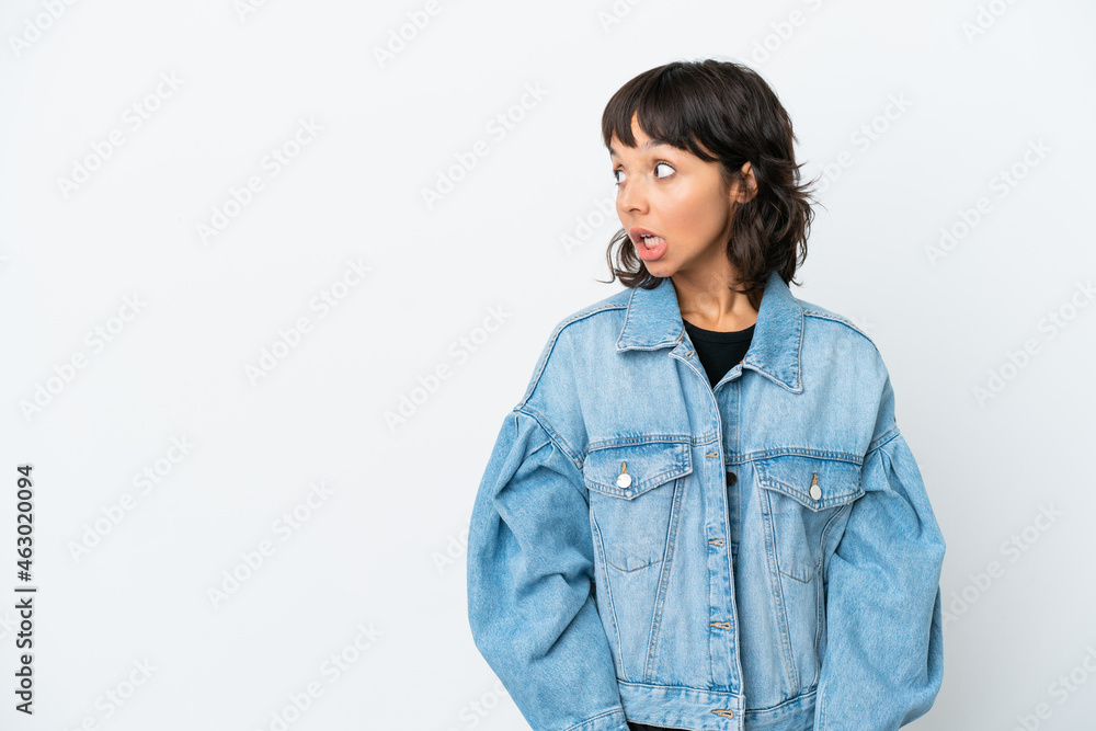 Young mixed race woman isolated on white background doing surprise gesture while looking to the side Young mixed race woman isolated on white background doing surprise gesture while looking to the side