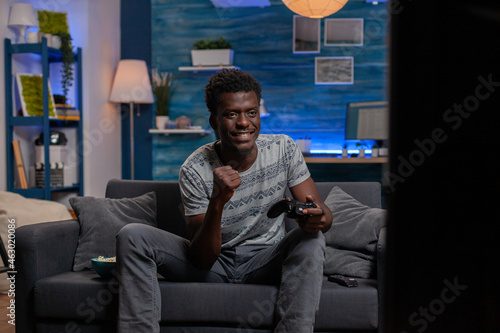 African american gamer winner playing online videogame winning space shoother competition using gaming controller. Black young man enjoying spending free time at home. Virtual game on tv photo