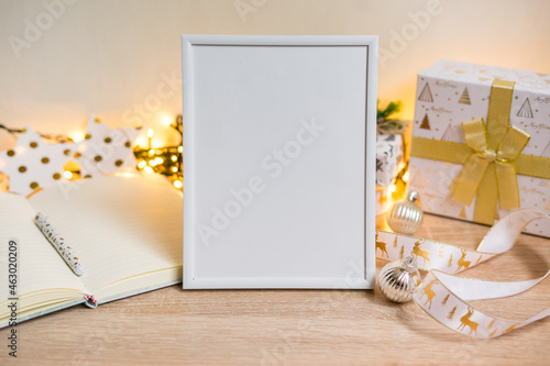 Portrait white picture frame mockup with christmas gifts, boken lights photo