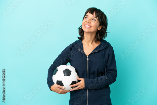Young mixed race football player woman isolated on blue background thinking an idea while looking up