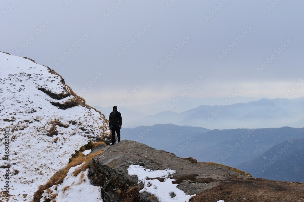 A man stands peacefully on the top of snow mountain.