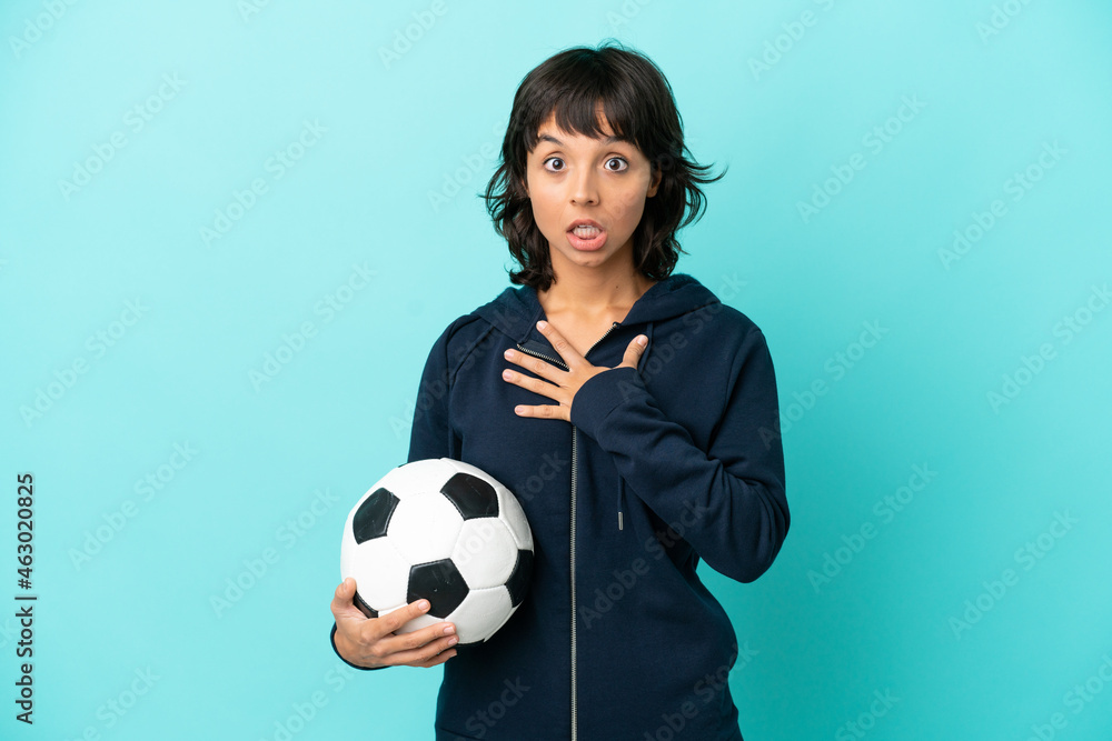Young mixed race football player woman isolated on blue background surprised and shocked while looking right Young mixed race football player woman isolated on blue background surprised and shocked while looking right