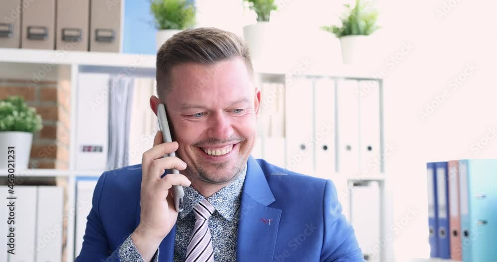 Young man in suit talking on cell phone in office and smiling 4k movie Young man in suit talking on cell phone in office and smiling 4k movie