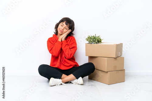 Young girl moving in new home among boxes isolated on white background making sleep gesture in dorable expression
