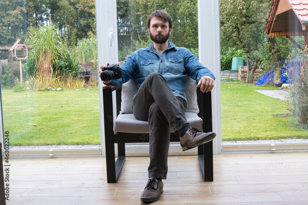 Bearded photographer posing in chair with his digital camera. Bearded photographer posing in chair with his digital camera.