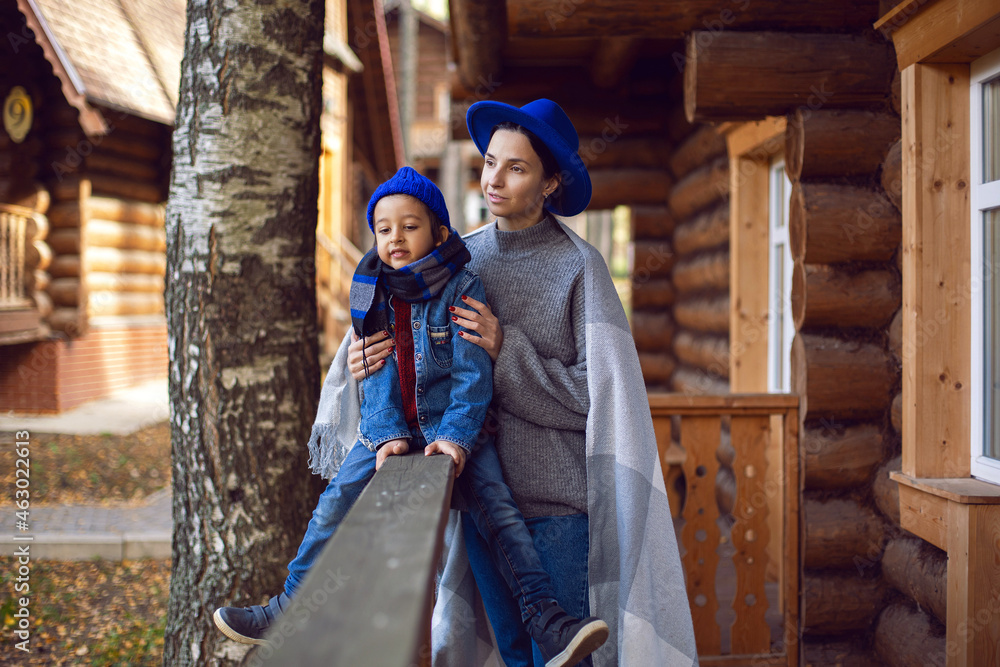 mom in a sweater and a blue hat with a child sitting on the porch