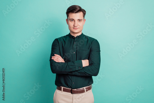 Portrait of happy marketer man crossing hands isolated over teal background