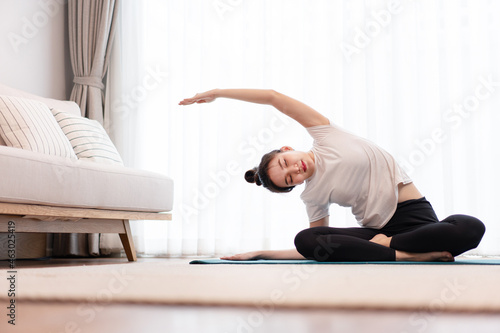 Productive activity concept a female young adult wearing a white t-shirt practicing the flexibility of her body by doing mat pilates