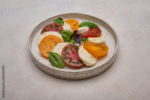 Close up caprese salad with red and yellow tomatoes, fresh basil and mozzarella cheese 