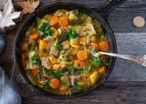 Pork stew with vegetables, pumpkin, potatoes in a cast iron skillet