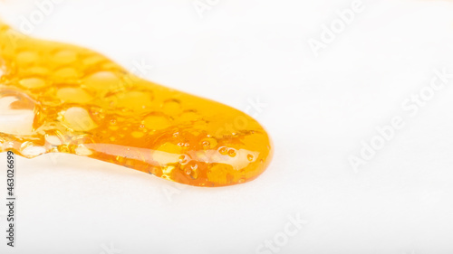 spreading drop of gold cannabis concentrate, wax with a high content of THC isolate