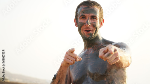 Male tourist rubbed in mud at the Dead Sea in Jordan.