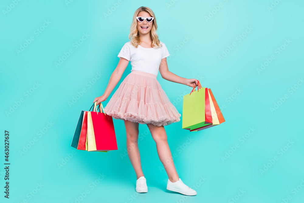 Photo of funny cute lady carry packages wear sunglass white t-shirt mini skirt shoes isolated aquamarine color background