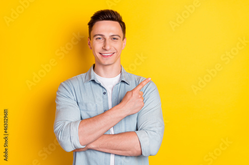 Portrait of attractive cheerful guy demonstrating copy empty space ad isolated over bright yellow color background