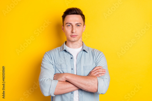 Portrait of young cool serious representative boss businessman with folded crossed hands isolated on yellow color background