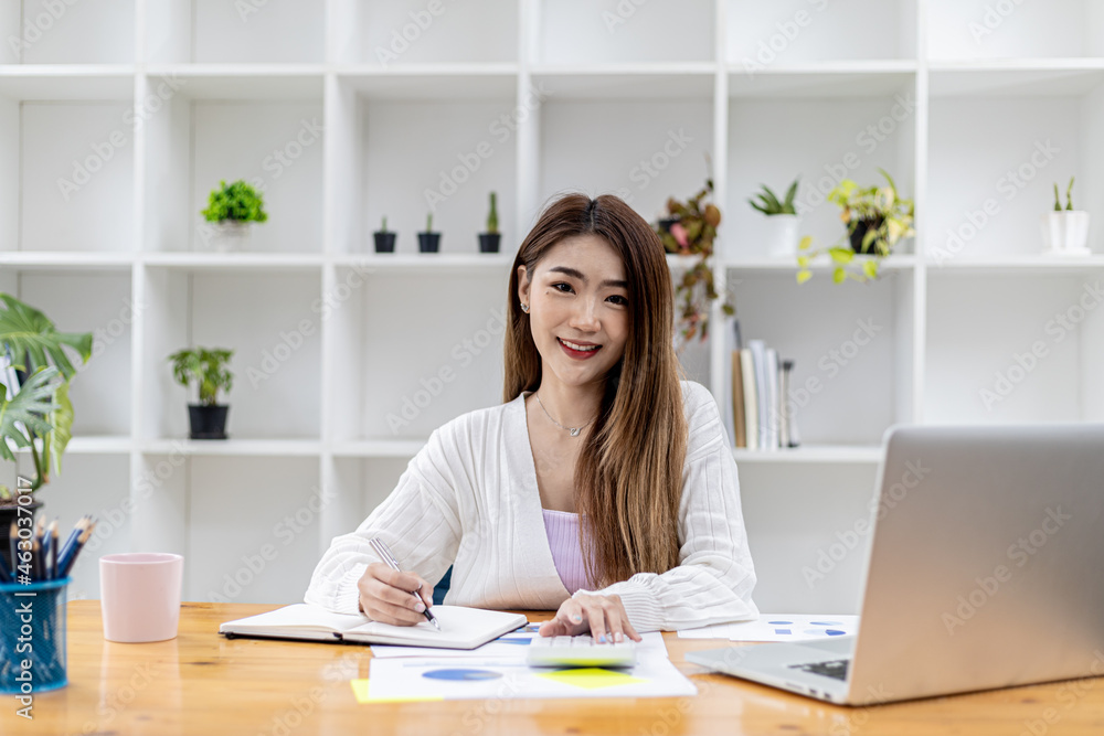 A beautiful Asian businesswoman sitting in her private office, she is checking company financial documents, she is a female executive of a startup company. Concept of financial management. A beautiful Asian businesswoman sitting in her private office, she is checking company financial documents, she is a female executive of a startup company. Concept of financial management.