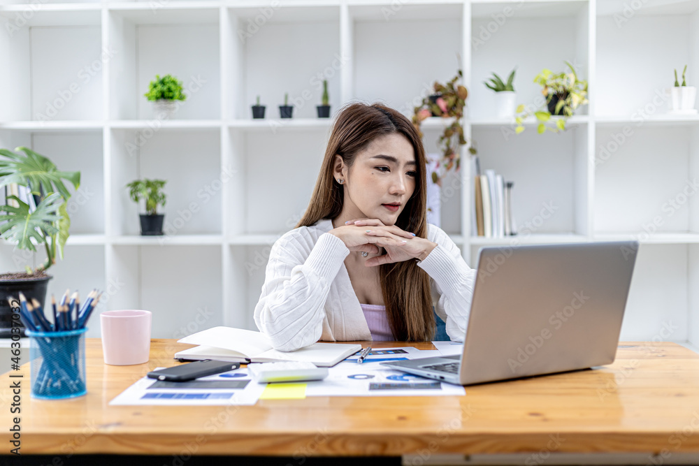 Beautiful Asian young woman looking at information on a laptop, concept image of Asian business woman working smart, modern female executive, startup business woman, business leader woman. Beautiful Asian young woman looking at information on a laptop, concept image of Asian business woman working smart, modern female executive, startup business woman, business leader woman.