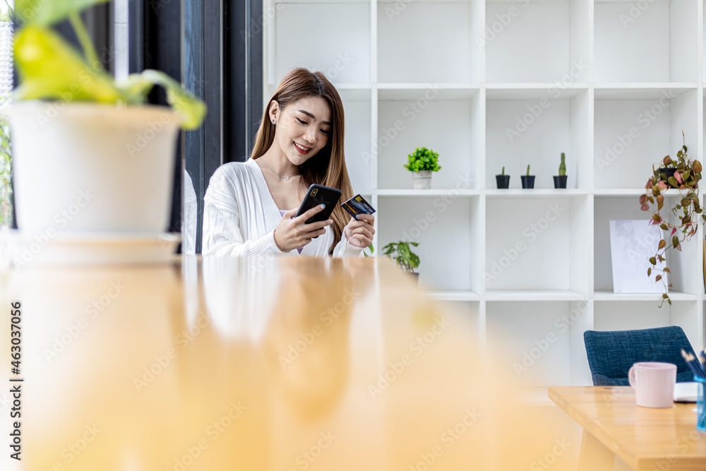 Beautiful Asian woman standing with smart phone and credit card, she fills in credit card information to pay for goods and services, online shopping concept pay by credit card and use via smartphone. Beautiful Asian woman standing with smart phone and credit card, she fills in credit card information to pay for goods and services, online shopping concept pay by credit card and use via smartphone.