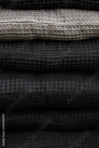 Waffle texture of textiles close-up. Grey gradient textiles with waffle texture stack on a shelf