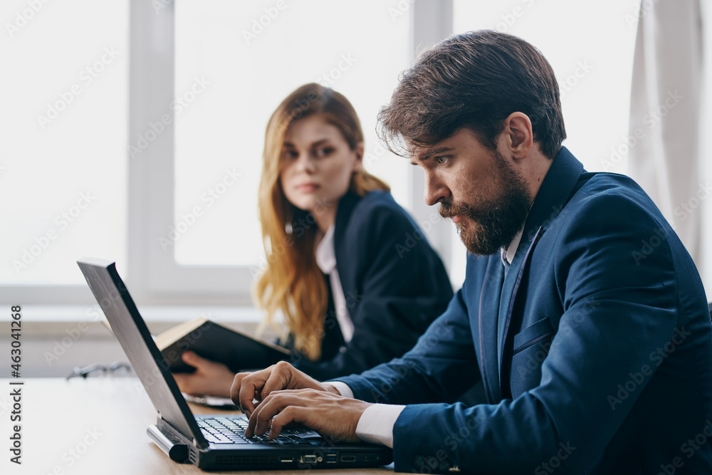 colleagues sitting at a desk with a laptop communication finance officials colleagues sitting at a desk with a laptop communication finance officials