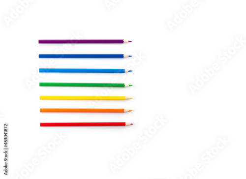 Colored pencils arranged according to the color of the rainbow on a white background.