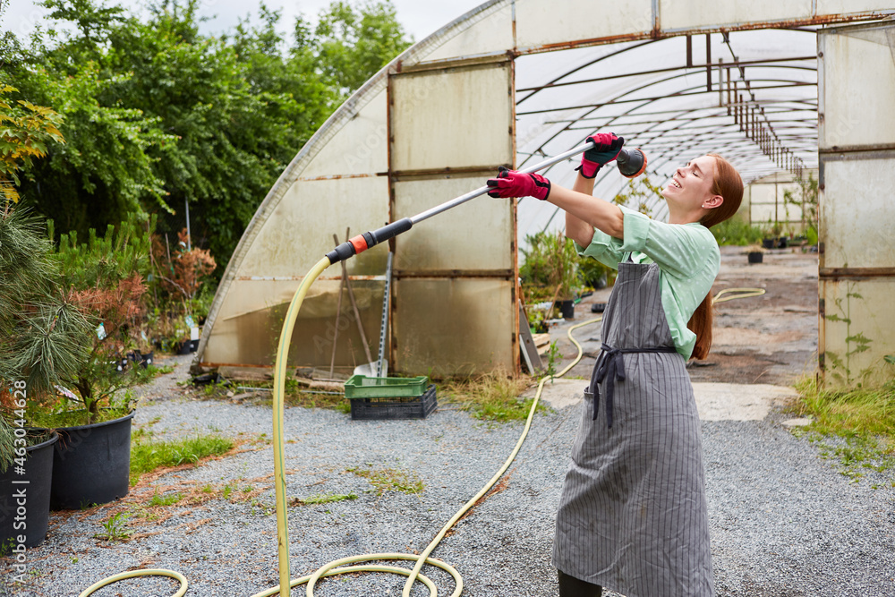 Gärtner Lehrling singt vor Freude in einen Gartenschlauch Stock Photo