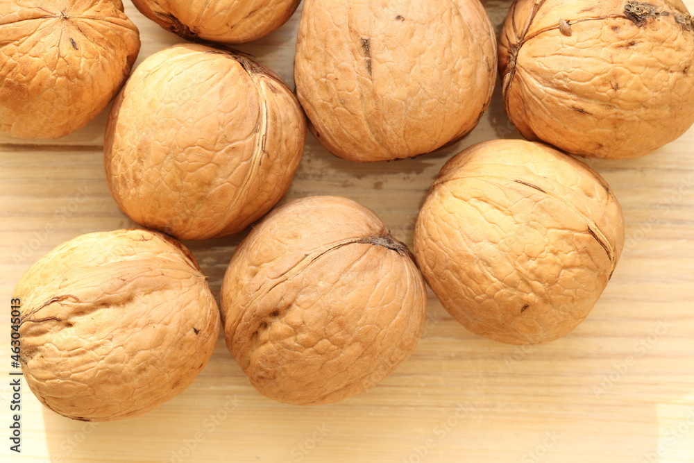 Walnut on a light wood background. Walnut is the fruit of a tree that can reach a height of 25 meters and live up to 400 years. Walnut on a light wood background. Walnut is the fruit of a tree that can reach a height of 25 meters and live up to 400 years.
