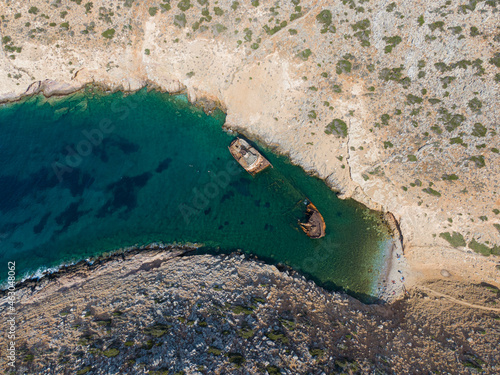aerial drone view of Shipwreck Olympia boat in Amorgos island during summer holidays, at the coastal rocky area, people on the beach, Cyclades, Greece. Travel background