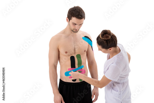 A therapist sticks bright kinesio tapes to stomach of a man © Volodymyr Shcerbak