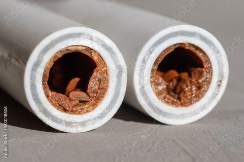 Old broken sludge plumbing polypropylene pipes with red rust and limescale on concrete background with copy space. Corrosion, sludge, limescale and hard water concept photo