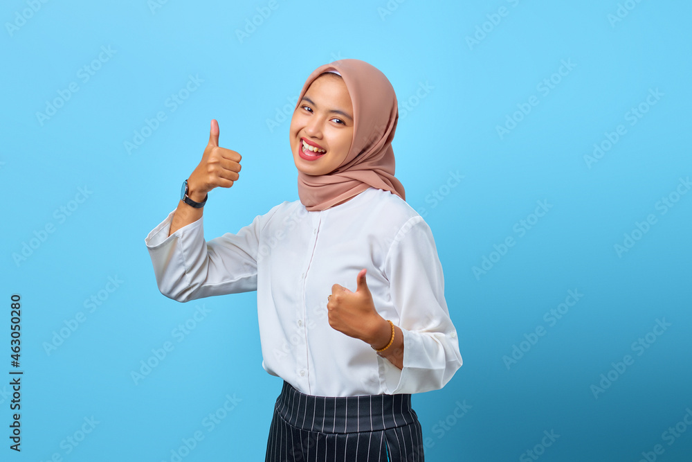 Portrait of excited cheerful young Asian woman showing thumbs up or approval sign Portrait of excited cheerful young Asian woman showing thumbs up or approval sign