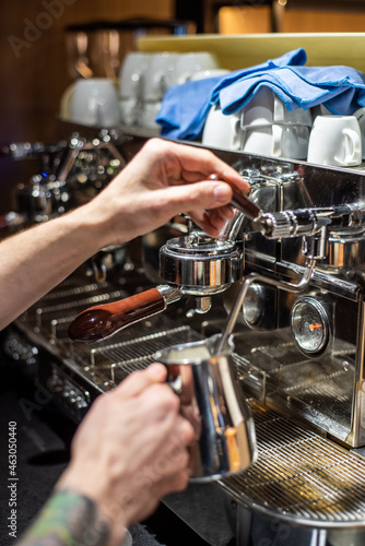 Closeup image of male hands pouring milk and preparing fresh cappuccino, coffee artist and preparation concept, morning coffee