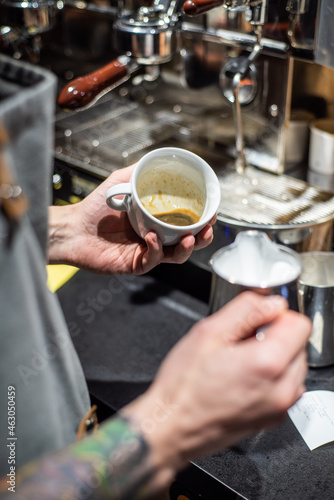 Closeup image of male hands pouring milk and preparing fresh cappuccino  coffee artist and preparation concept  morning coffee