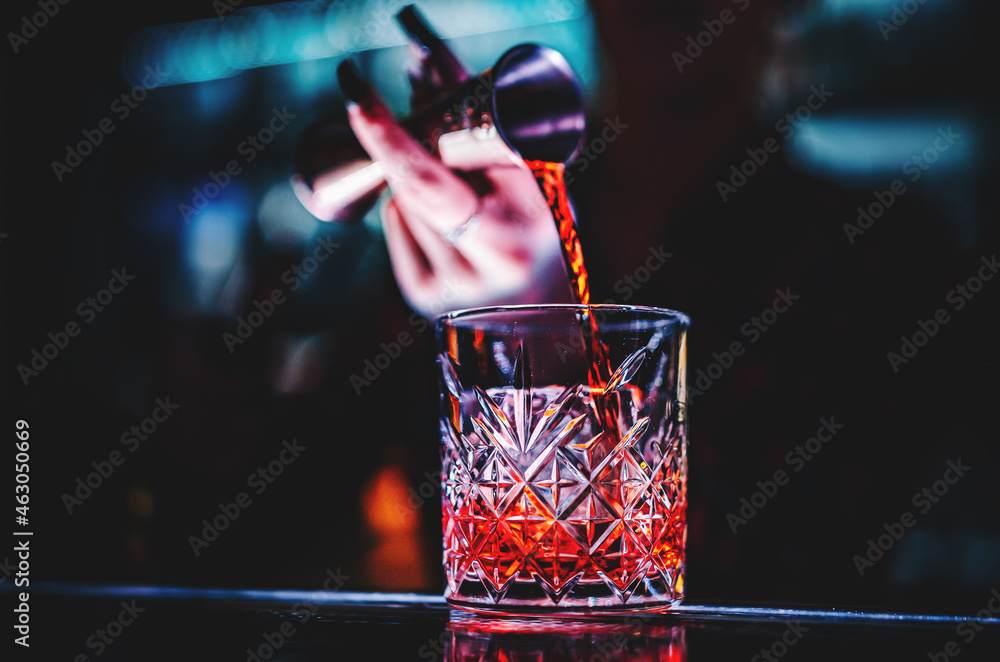 woman bartender hand making negroni cocktail. Negroni classic cocktail and gin short drink with sweet vermouth, red bitter liqueur - obrazy, fototapety, plakaty 