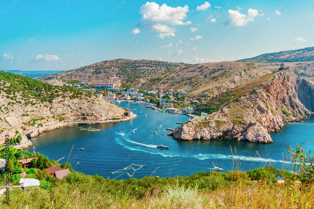 Fototapeta premium A picturesque panorama of the Balaclava view with yachts and a colorful bay in summer. Postcard view of the tourist Crimea.