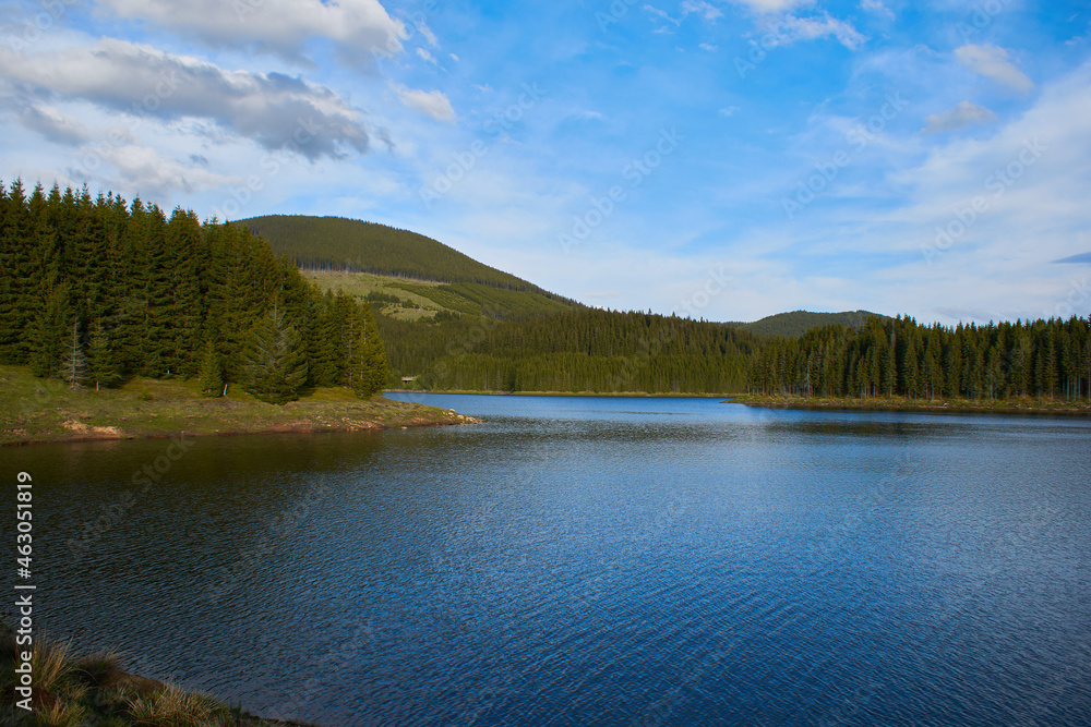 A view over the Lake Oasa in Mountains Sureanu with sky with clouds and forest A view over the Lake Oasa in Mountains Sureanu with sky with clouds and forest
