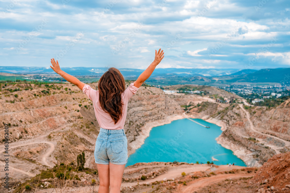 A happy young beautiful woman at the Kadykovsky quarry in the shape of a heart with turquoise water in the Crimea. Beautiful landscape A happy young beautiful woman at the Kadykovsky quarry in the shape of a heart with turquoise water in the Crimea. Beautiful landscape