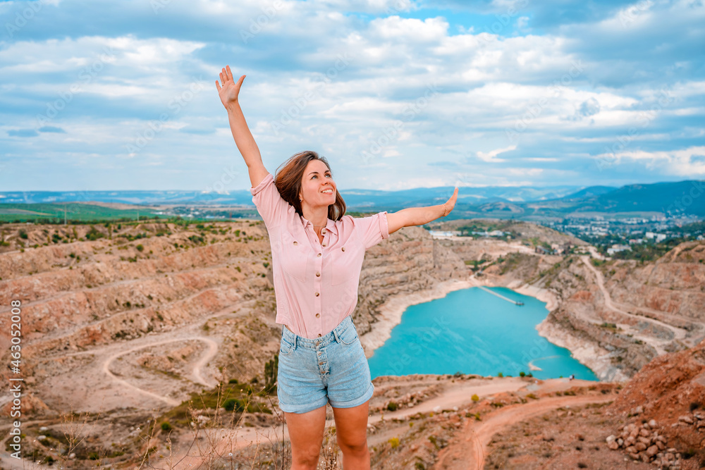 A happy young beautiful woman at the Kadykovsky quarry in the shape of a heart with turquoise water in the Crimea. Beautiful landscape A happy young beautiful woman at the Kadykovsky quarry in the shape of a heart with turquoise water in the Crimea. Beautiful landscape