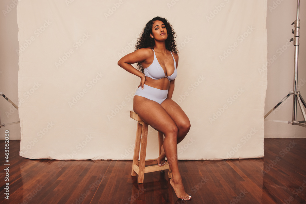 Young woman sitting comfortably in blue underwear - obrazy, fototapety, plakaty 