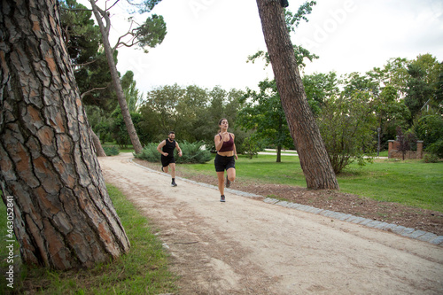 Fototapeta Naklejka Na Ścianę i Meble -  young caucasian man and woman couple running in a park