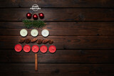 Christmas tree made of candles, fir branches, cones, christmas balls and vanilla sticks on a wooden background