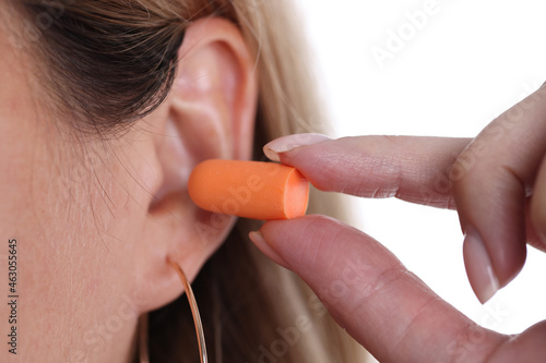Foto Woman inserts orange earplugs into ears closeup