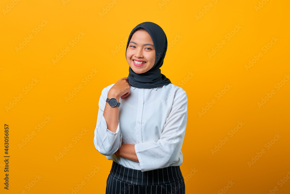 Cheerful young Asian woman raised hand with crossed arm isolated over yellow background Cheerful young Asian woman raised hand with crossed arm isolated over yellow background