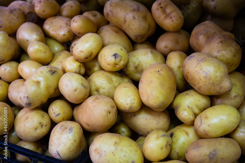 Pile of ripe potatoes in plastic box on showcase of greengrocery..