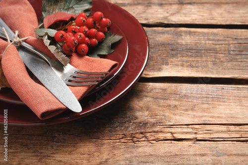 Festive table setting with ashberries on wooden background, closeup. Space for text photo